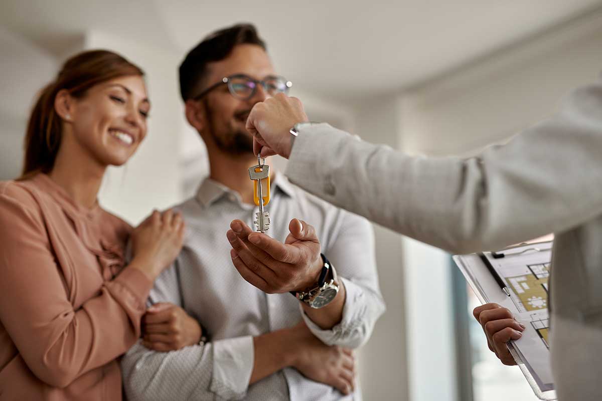 closeup real estate agent giving couple keys their new home